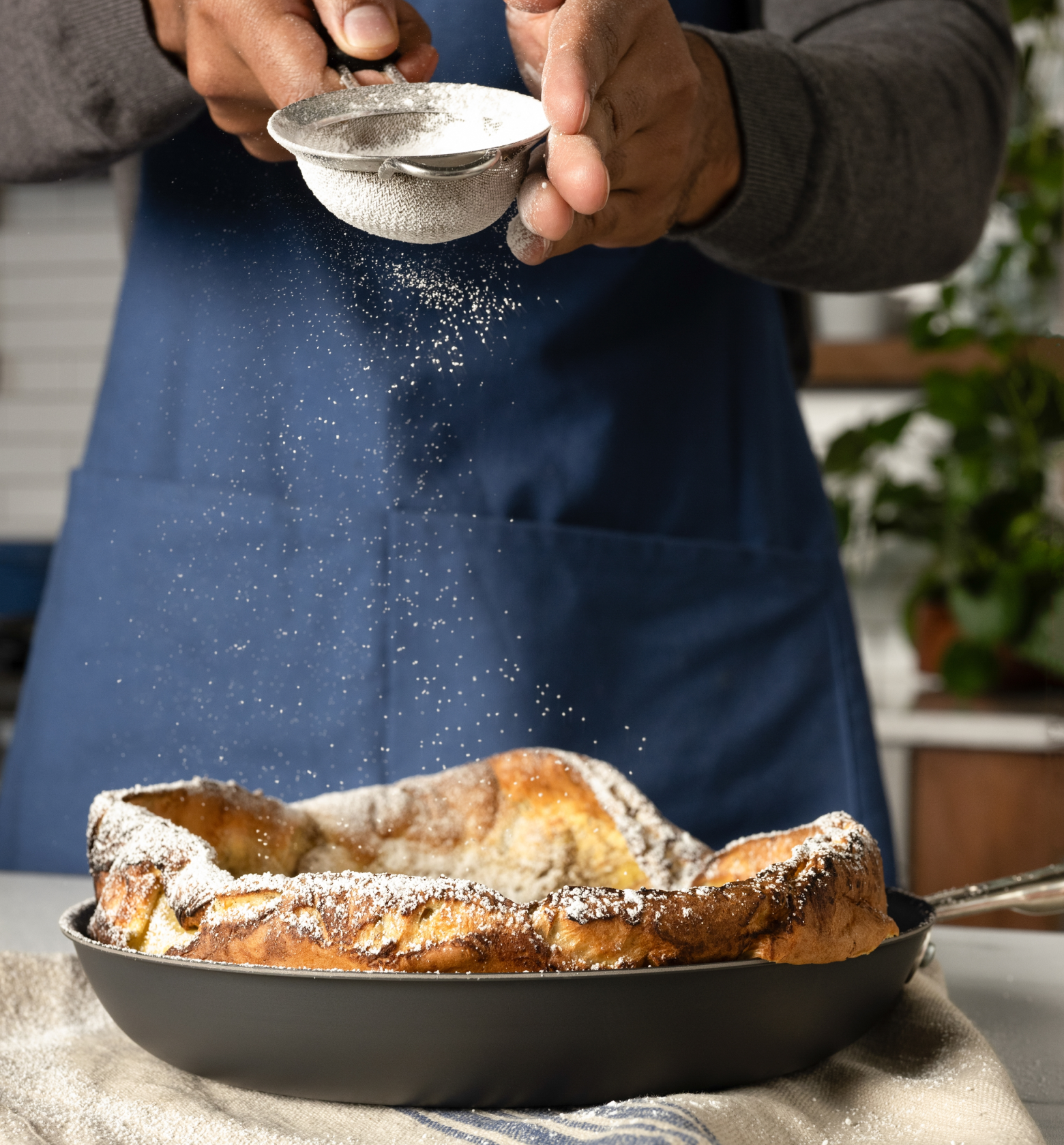 Dutch baby pancake dusted with powdered sugar in cast iron skillet